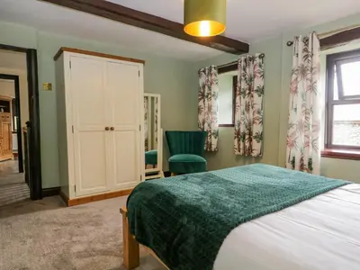 a bedroom with a bed and a chair and a window at Ewedale Farm in Ulverston