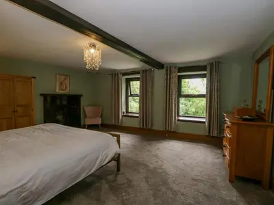 a bedroom with a bed and two windows at Ewedale Farm in Ulverston