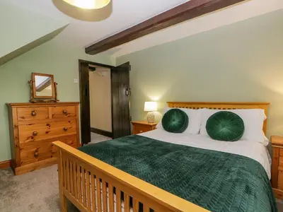 a bedroom with a bed with a green comforter at Ewedale Farm in Ulverston