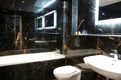 a black tiled bathroom with a toilet and a sink at Best Western Hotel 99 in Blackburn
