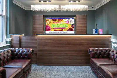 a waiting room with two leather chairs and a tv at Best Western Hotel 99 in Blackburn