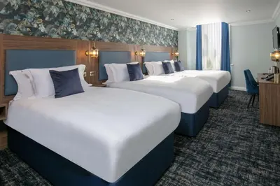 a row of four beds in a hotel room at Best Western Hotel 99 in Blackburn