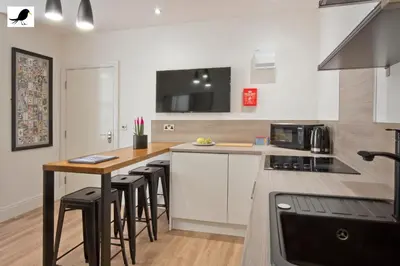 a kitchen with a counter and a table with bar stools at Blackbird Accommodation and Luxury Apartments room 12 in Blackpool