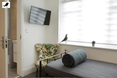 a living room with a chair and a tv and a window at Blackbird Accommodation and Luxury Apartments room 12 in Blackpool
