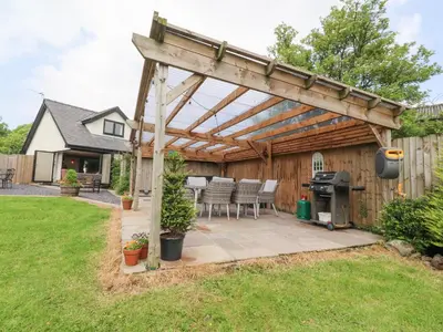a wooden pergola with a grill in a backyard at Old Bell Works in Preston