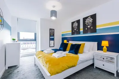 a bedroom with a large bed with yellow and blue at Bright, Luxury Aparthotel, Excellent Location in Liverpool