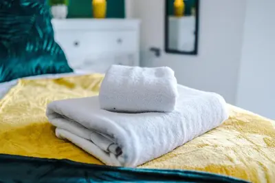 a pile of towels sitting on top of a bed at Bright, Luxury Aparthotel, Excellent Location in Liverpool
