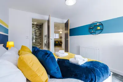 a room with a bed with blue and yellow pillows at Bright, Luxury Aparthotel, Excellent Location in Liverpool