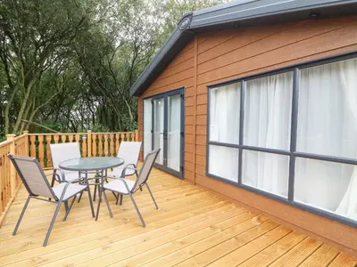 a patio with a table and chairs on a deck at Barney's Retreat in Carnforth