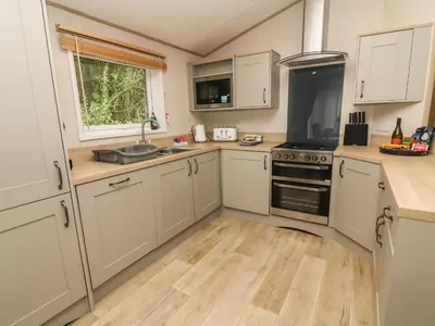 a kitchen with white cabinets and a stove top oven at Barney's Retreat in Carnforth