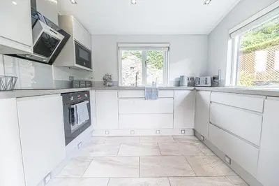 a kitchen with white cabinets and a tile floor at North Lodge Cartmel in Cartmel