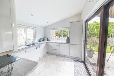 a kitchen with white cabinets and a large window at North Lodge Cartmel in Cartmel