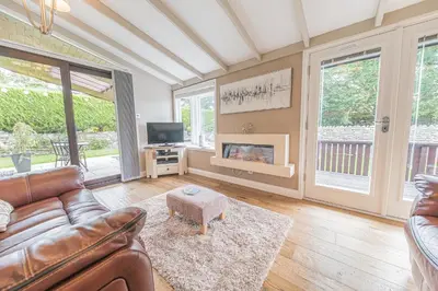 a living room with a leather couch and a fireplace at North Lodge Cartmel in Cartmel
