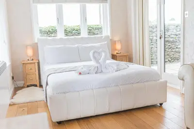 a white bed in a room with two lamps at North Lodge Cartmel in Cartmel