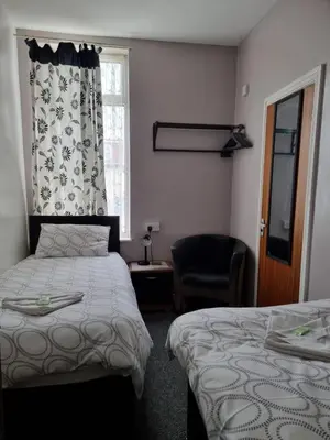 a bedroom with two beds and a chair and a window at Casablanca in Blackpool