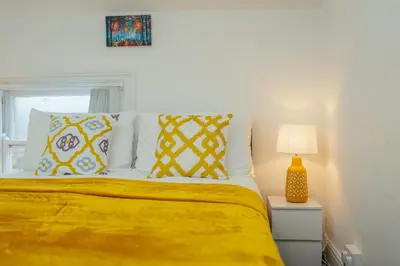 a bedroom with a bed with yellow sheets and pillows at Crosby Apartments in Liverpool