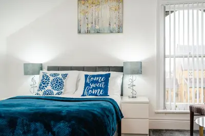 a bedroom with a bed with blue and white pillows at Crosby Apartments in Liverpool