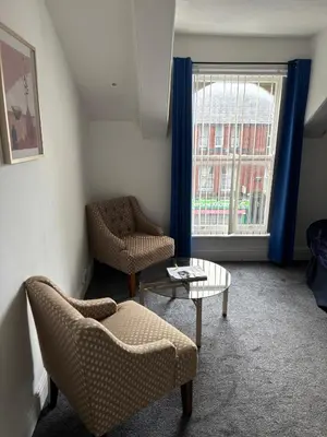 a living room with chairs and a table and a window at Crosby Apartments in Liverpool