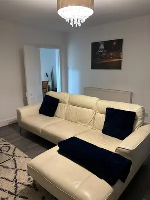 a white couch in a living room with a chandelier at Crosby Apartments in Liverpool