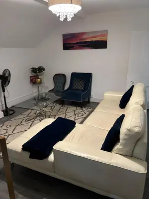 a living room with a white couch and blue chairs at Crosby Apartments in Liverpool