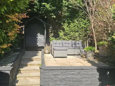 a couch sitting in a gazebo in a garden at Shakespeare’s Nest in Prescot