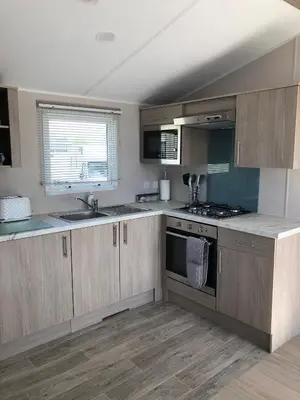 a kitchen with wooden cabinets and a sink and a stove at Tranquility No 42 Port Haverigg Marina in Millom