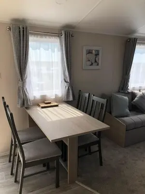 a dining room table with chairs and a couch at Tranquility No 42 Port Haverigg Marina in Millom