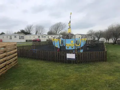 a playground in a park with a wooden fence at Tranquility No 42 Port Haverigg Marina in Millom
