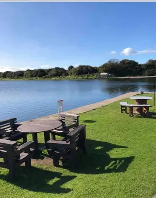 a picnic table and benches next to a body of water at Tranquility No 42 Port Haverigg Marina in Millom