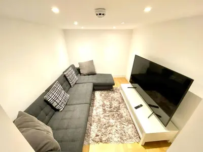 a living room with a gray couch and a flat screen tv at Beautiful Georgian Mansion! by City Sparrow in Liverpool