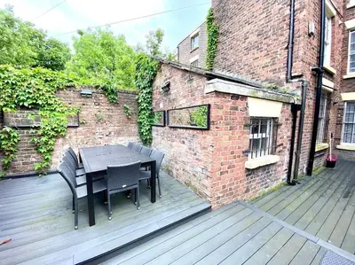 a table and chairs on a wooden deck next to a brick building at Beautiful Georgian Mansion! by City Sparrow in Liverpool