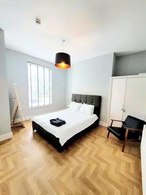 a bedroom with a bed and a black chair at Beautiful Georgian Mansion! by City Sparrow in Liverpool