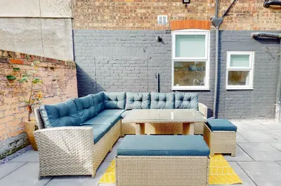 a patio with a blue couch and a table at Lancefield House - Air Host & Stay - 5 Bedroom Sleeps 15 in Walton on the Hill