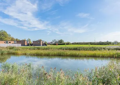 a pond in a field with buildings in the background at Waterside Hambleton Lakeside Lodges in Poulton le Fylde