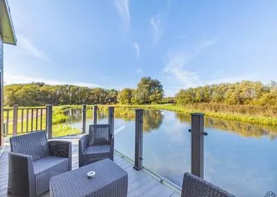 a deck with chairs and a view of a river at Waterside Hambleton Lakeside Lodges in Poulton le Fylde
