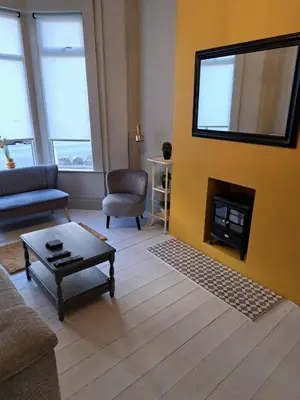 a living room with a yellow wall with a fireplace at Three Bedroomed House in Morecambe in Morecambe