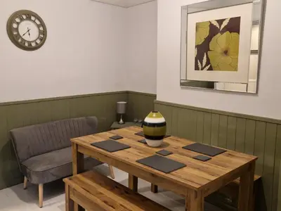 a wooden table in a room with a clock on the wall at Three Bedroomed House in Morecambe in Morecambe