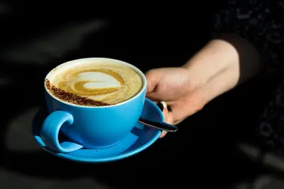 a person holding a blue cup of coffee at The Lake House in Liverpool