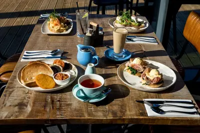 a wooden table with plates of food and a cup of coffee at The Lake House in Liverpool