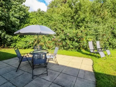a patio with a table and chairs and an umbrella at Number 15 in Carnforth