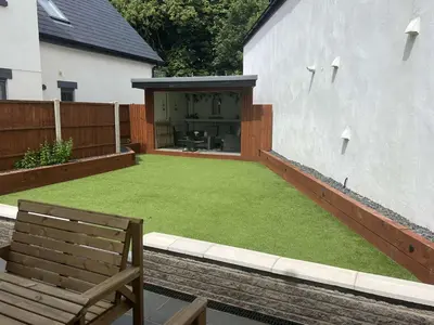 a backyard with a lawn with a bench and a building at Old Smithy Cottage in Great Singleton