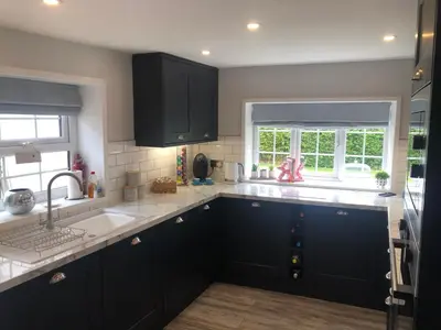 a kitchen with black cabinets and a sink and a window at Old Smithy Cottage in Great Singleton