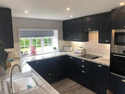 a kitchen with black cabinets and a sink at Old Smithy Cottage in Great Singleton