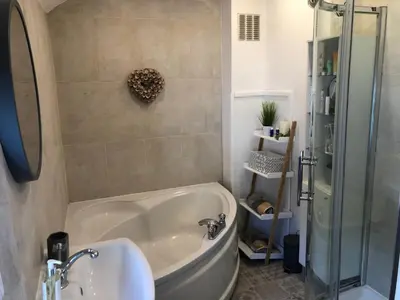 a bathroom with a tub and a sink and a shower at Old Smithy Cottage in Great Singleton