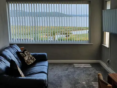 a living room with a couch and a large window at Dolphin Cottage in Grange Over Sands