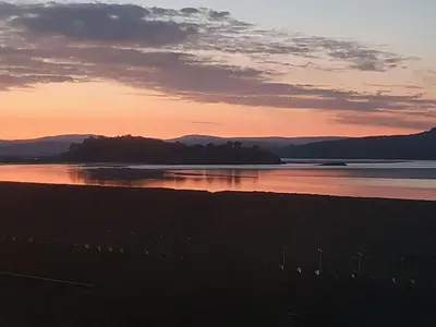 a sunset over a beach with mountains in the background at Dolphin Cottage in Grange Over Sands