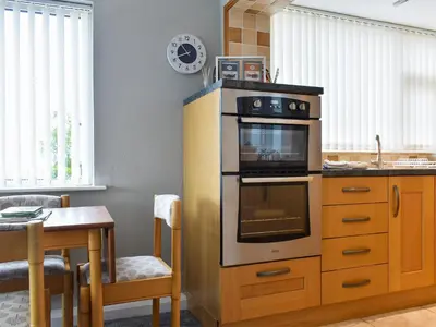 a kitchen with a stove and a table with a table at Dolphin Cottage in Grange Over Sands