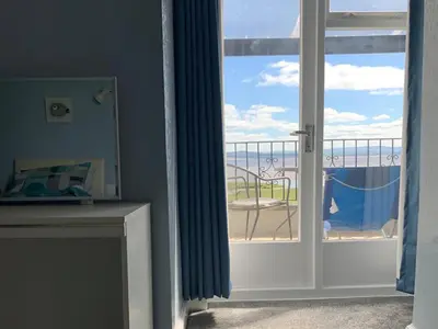 a room with a sliding glass door with a view of the beach at Dolphin Cottage in Grange Over Sands