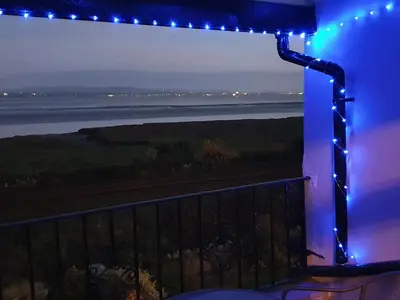 a view of the ocean from a balcony with blue lights at Dolphin Cottage in Grange Over Sands