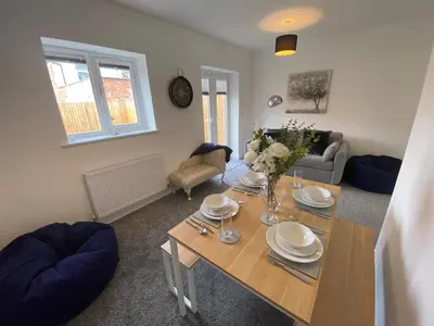a living room with a table with plates and flowers on it at Blackpool Abode - Silver Sands in Blackpool